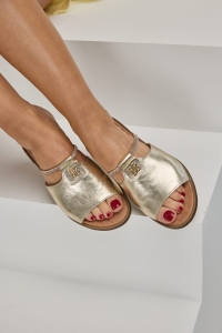 Złote klapki pokazane na stopach