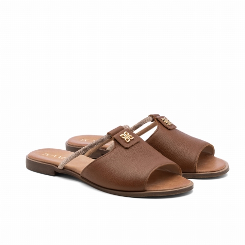 Na białym tle widoczna jest para brązowych klapek damskich ze skóry. Klapki mają odkryte palce i płaską podeszwę. Przód stopy zakrywa szeroki skórzany pasek. Z tyłu znajduje się cienki pasek przechodzący przez śródstopie