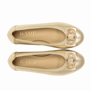 Dwie złote baleriny widziane z góry, z ozdobą w formie podwójnych kółek na przodzie i jasnym wnętrzem buta